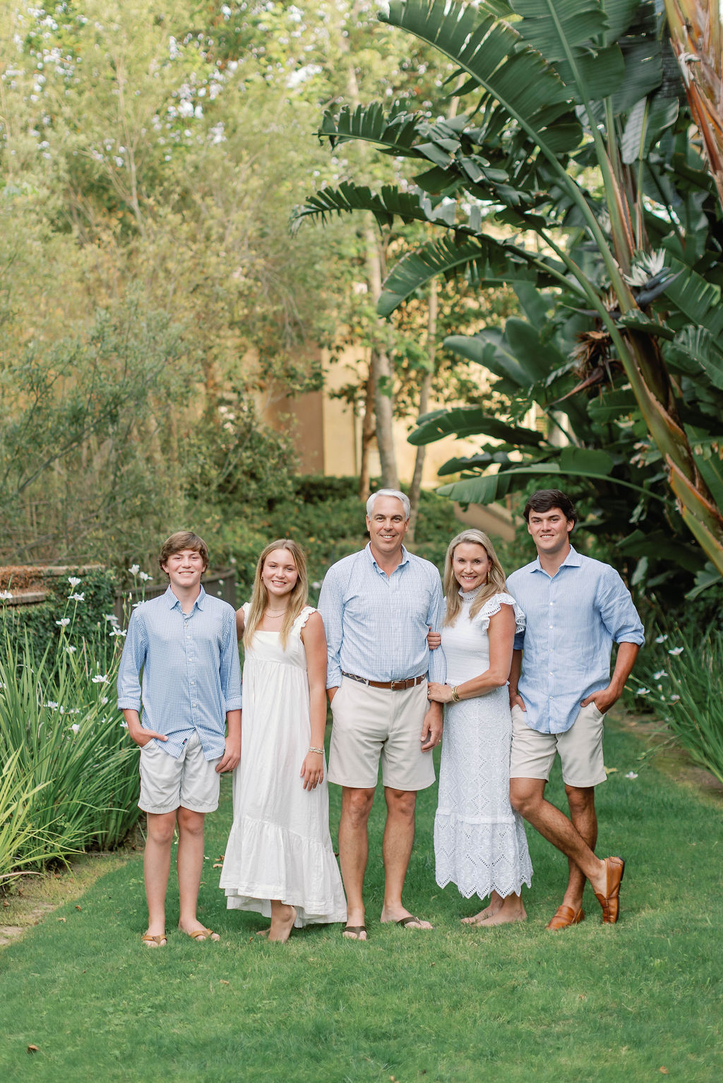 A family photo at Pelican Hill  California in the gardens with large Canary palms, flowers, stone wall and ivy.