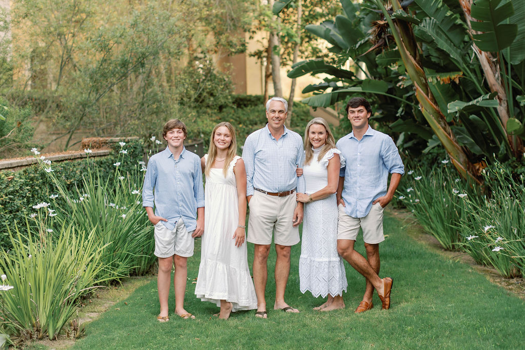 A  family smiling  for a family photo session at Pelican Hill,  California in the garden.