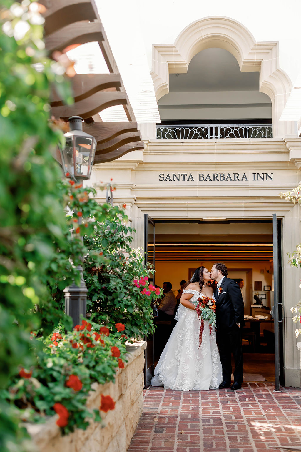 Bride and Groom kiss while standing under the doorway to the Santa Barbara Inn at Mission Santa Barbara wedding | Photo by Sarah Block Photography