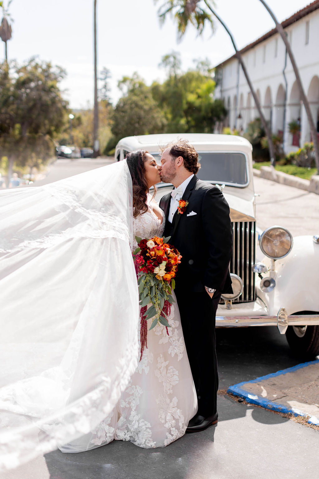 Bride and Groom kissing in front of the Rolls Royce at Mission Santa Barbara wedding | Photo by Sarah Block Photography