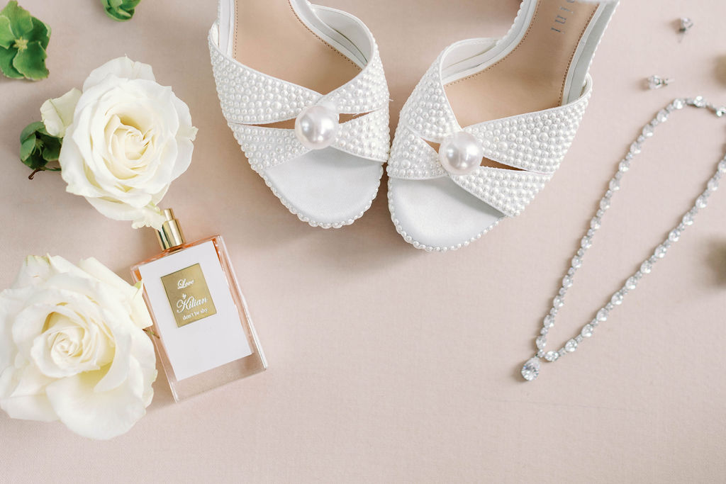 Detailed flat lay photo of brides pearl sandals and perfume at Mission Santa Barbara wedding | Photo by Sarah Block Photography