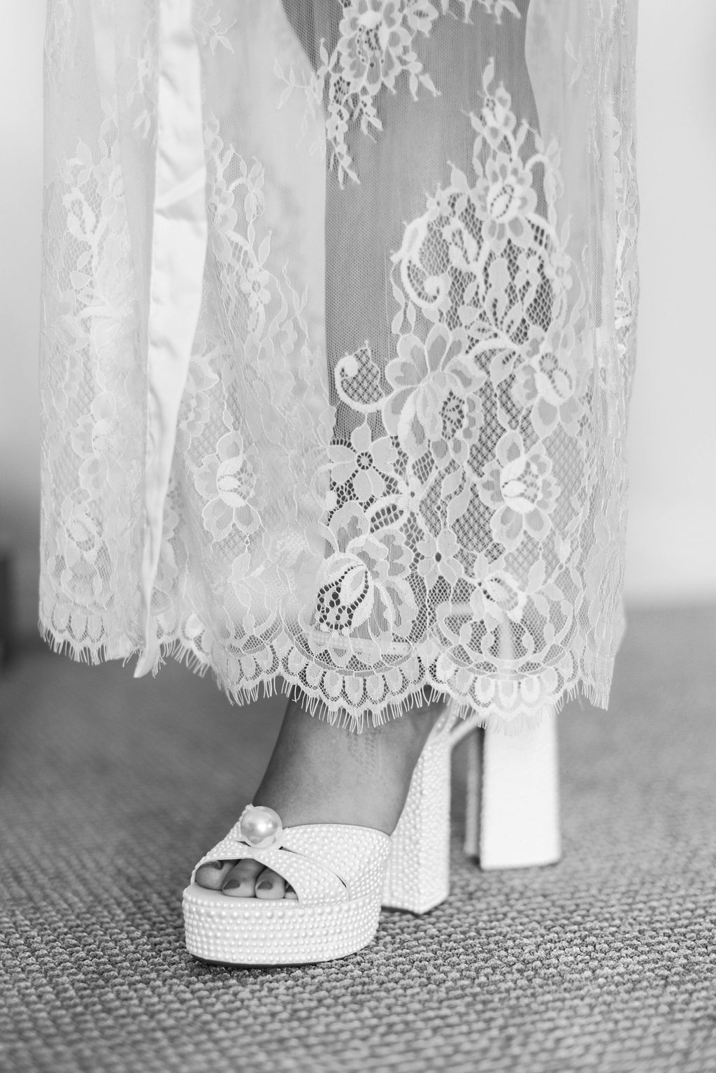 Brides leg showing edge of wedding gown with lace scalloped edges and eyelashes to soften the silhouette with her pearl sandals in a black and white photo at Mission Santa Barbara wedding | Photo by Sarah Block Photography