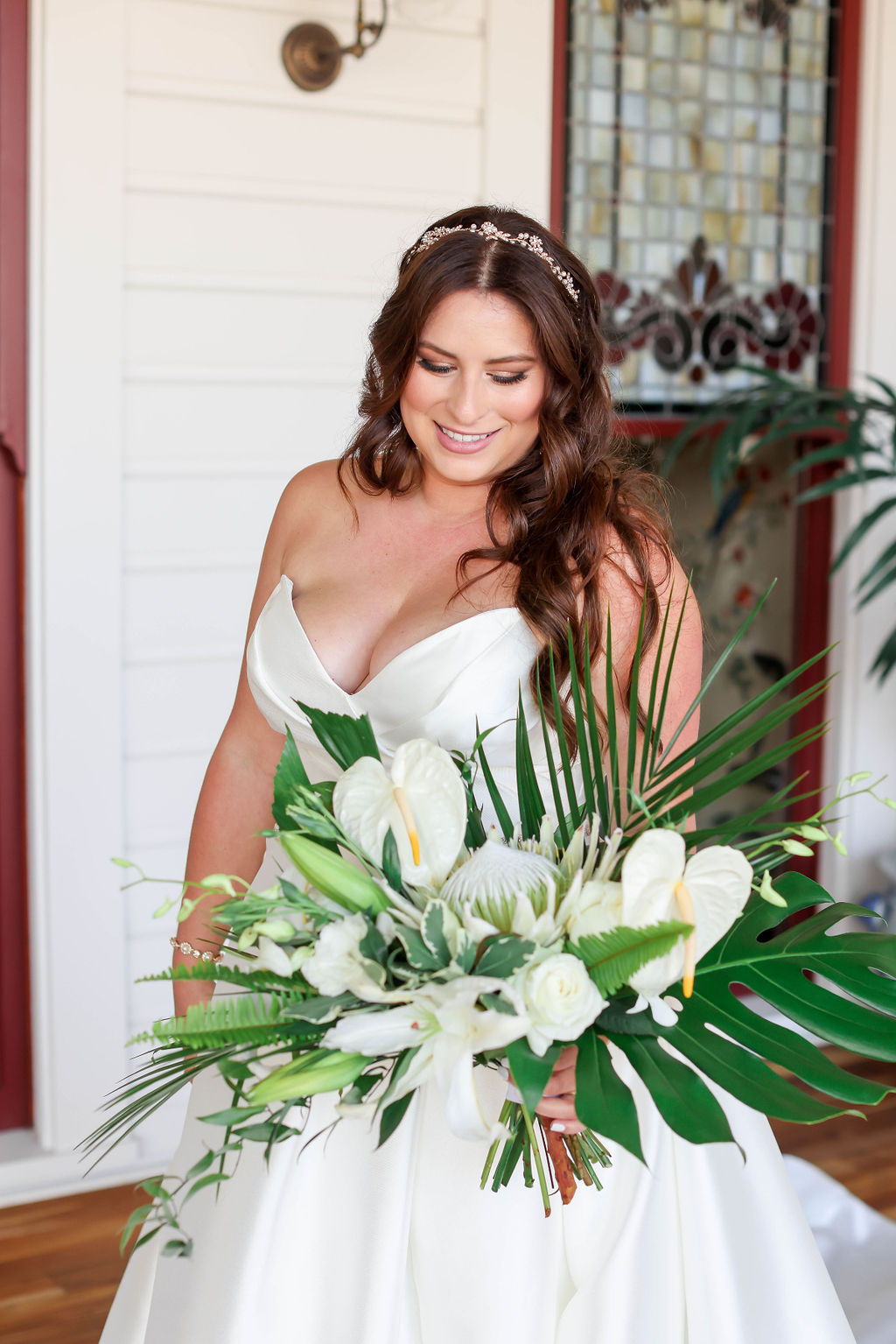 Photo of a bride at Hotel DEl-Coronado San Diego looking down at her wedding bouquet of white flowers and green palm. Photo by Sarah Block Photography.