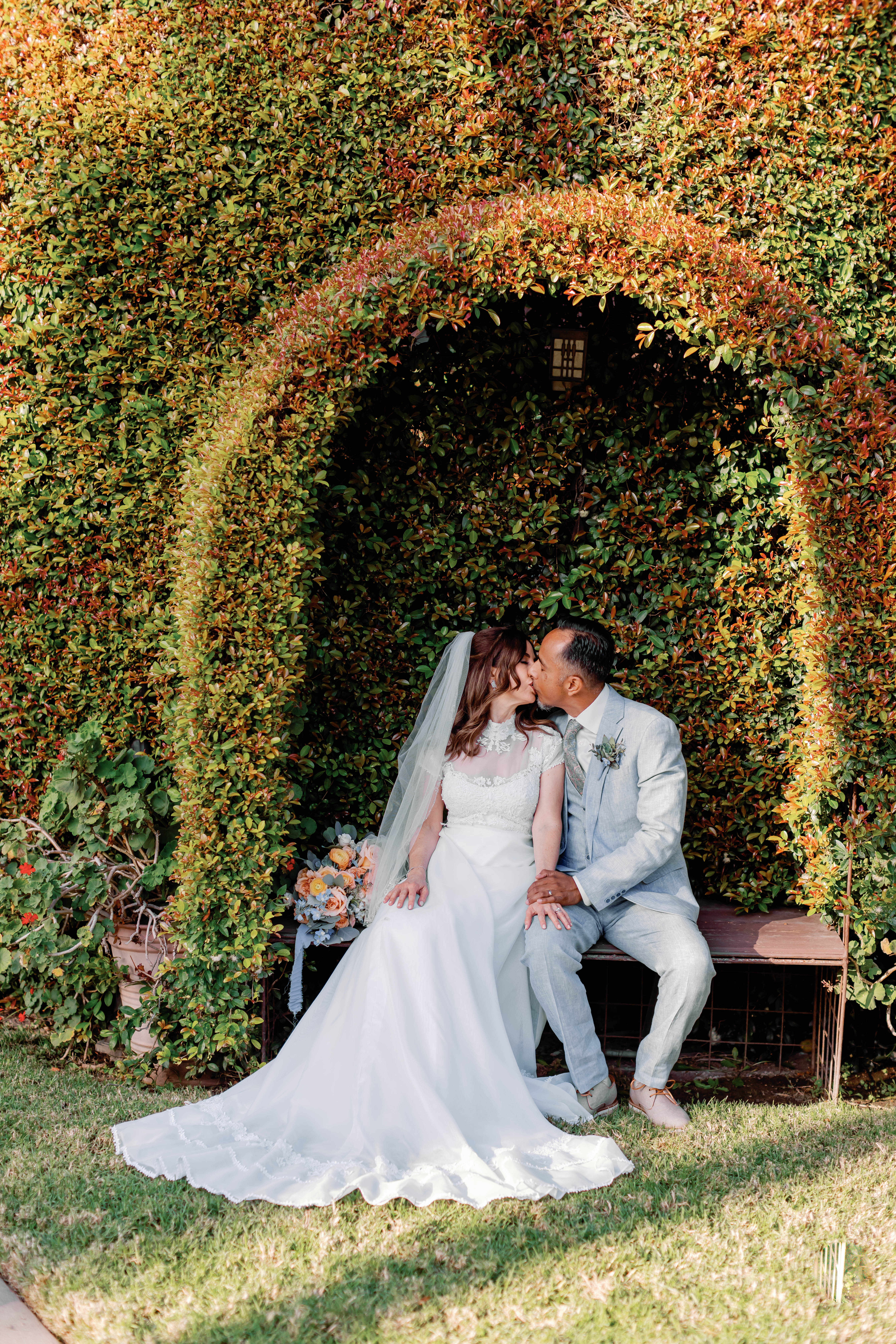 Bride and Groom kissing unde the arbor in the garden at Chapel of Orange | Photo by Sarah Block Photography