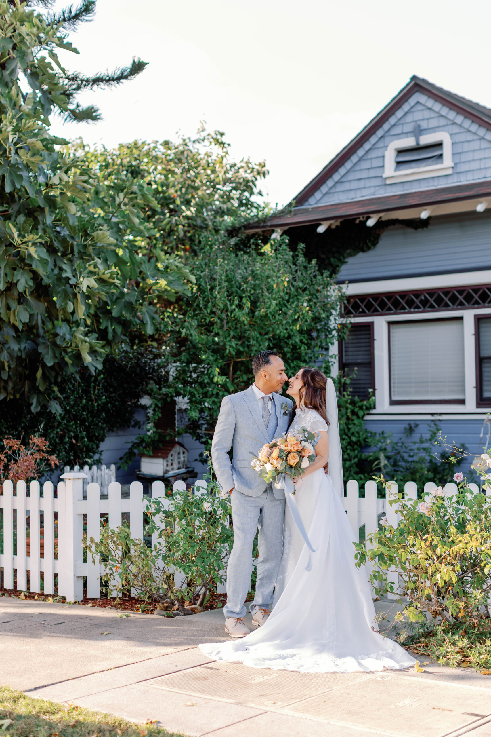 Bride and groom in front of the white picket fence by Chapel of Orange | Photo by Sarah Block Photography
