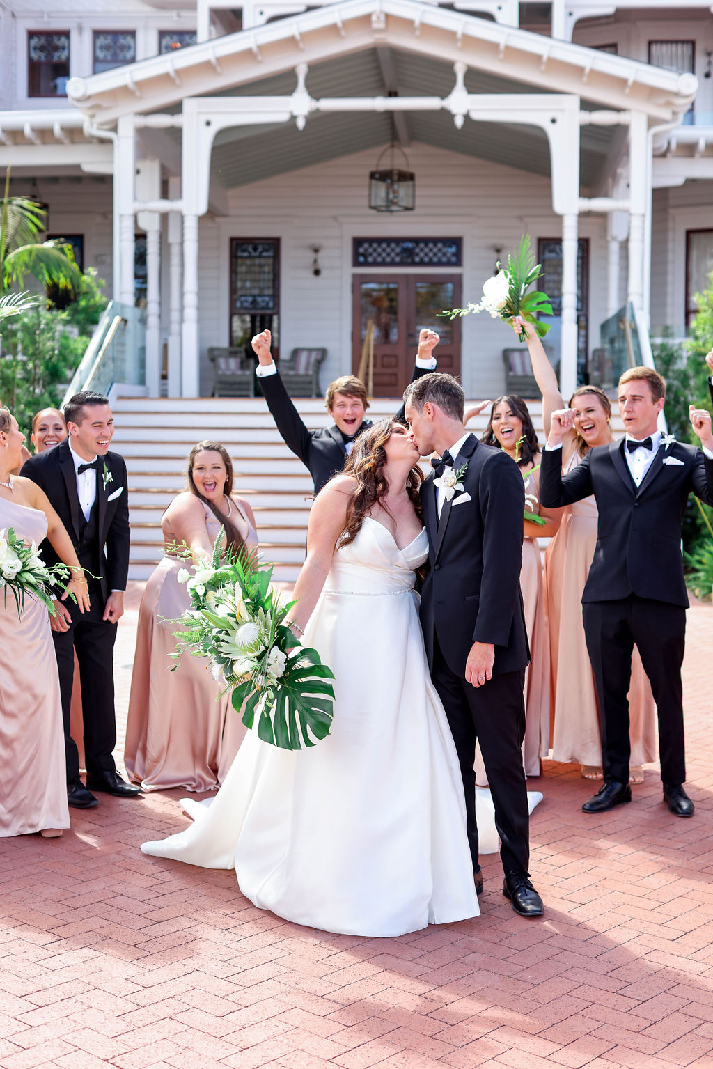 Group shot of Bride and groom kissing and bridal party cheering behind them at The Hotel Del Coronado in San Diego California |Photo by Sarah Block Photography.