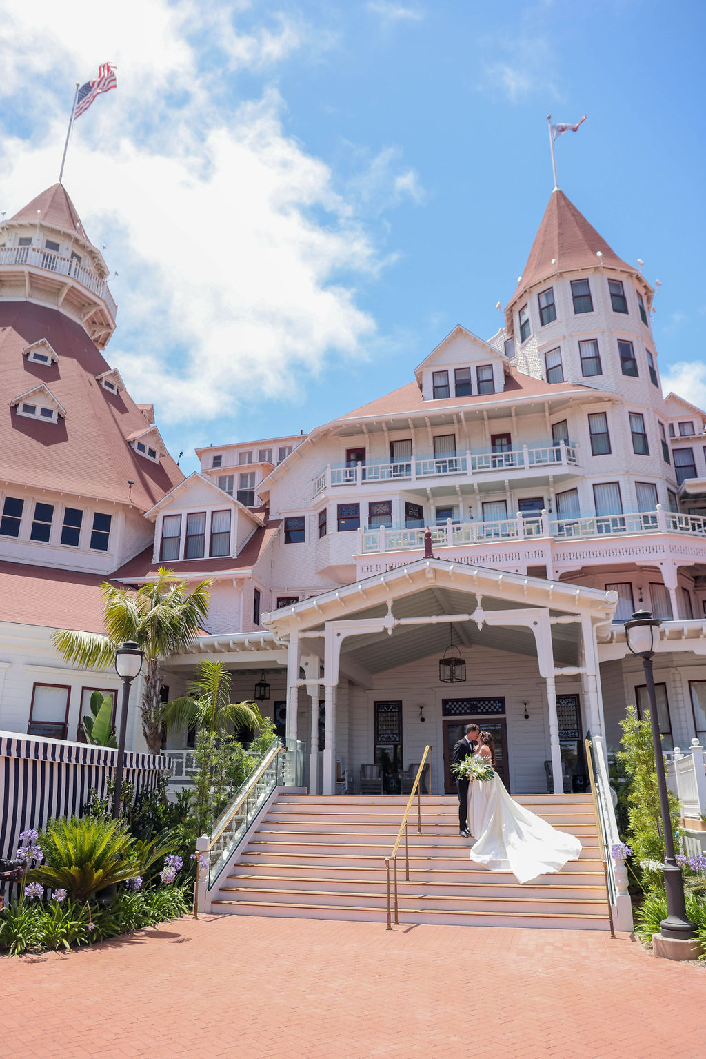 Bride and Groom standing and kissing on the steps of the Hotel Del Coronado Resort in San Diego California photo by Sarah Block Photography.