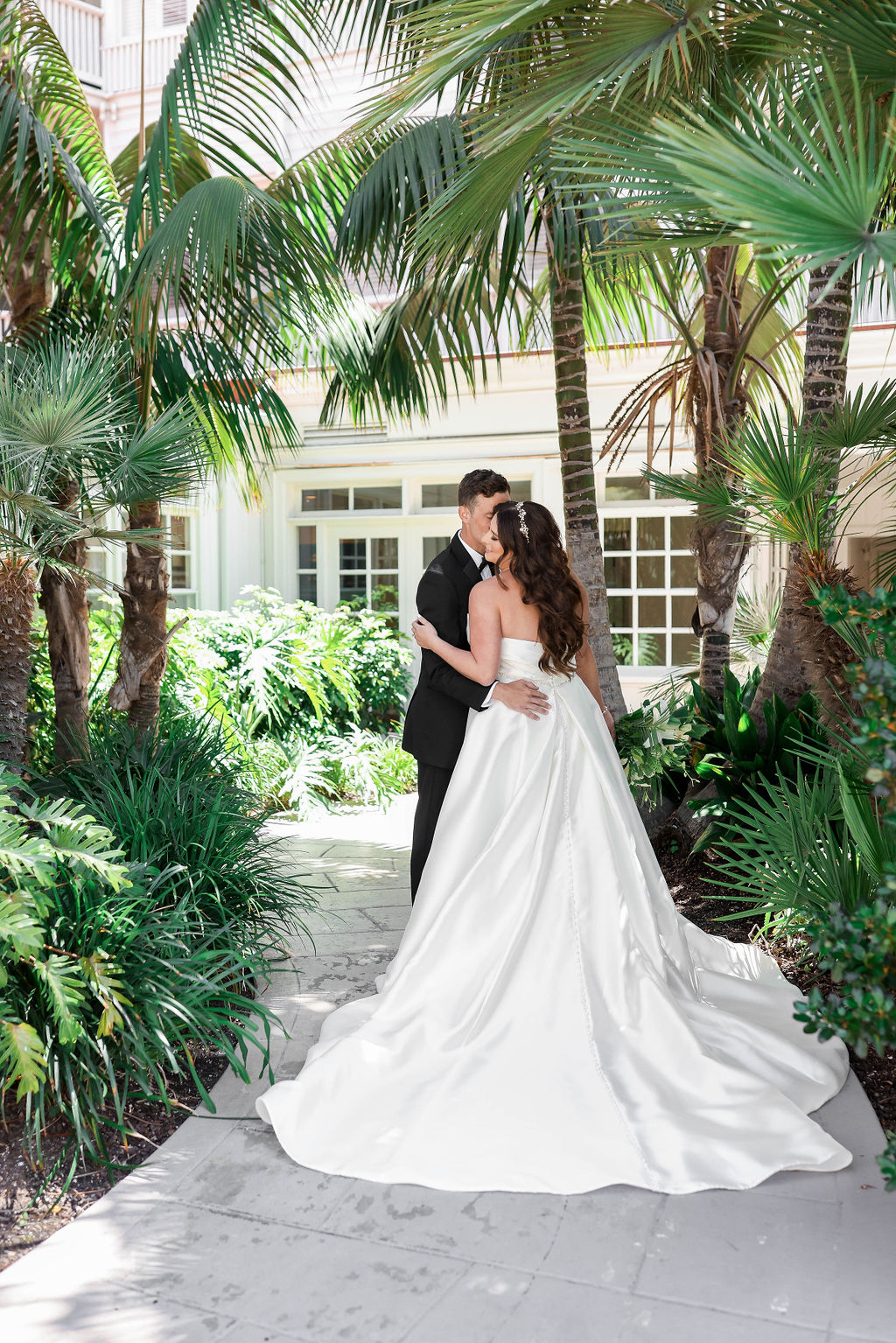 Bride and Groom embracing during their first look on their wedding day as they stand in the garden with palm trees surrounding them at the Hotel Del Coronado in San Diego California | Photo by Sarah Block Photography.
