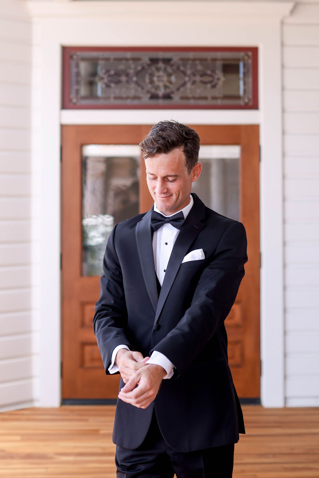 Candid photo of the groom as he fixes his cuff of his tuxedo standing at The Hotel Del Coronado on his wedding day. Photo by Sarah Block Photography.