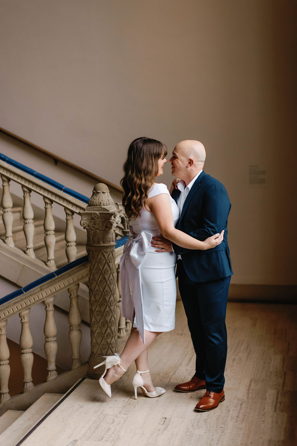 Engagement photo of Jimmy and Hannah at stairwell by the  bannister of the stairs at San Diego Museum of art. |Photo by California Photographer Sarah Block Photography