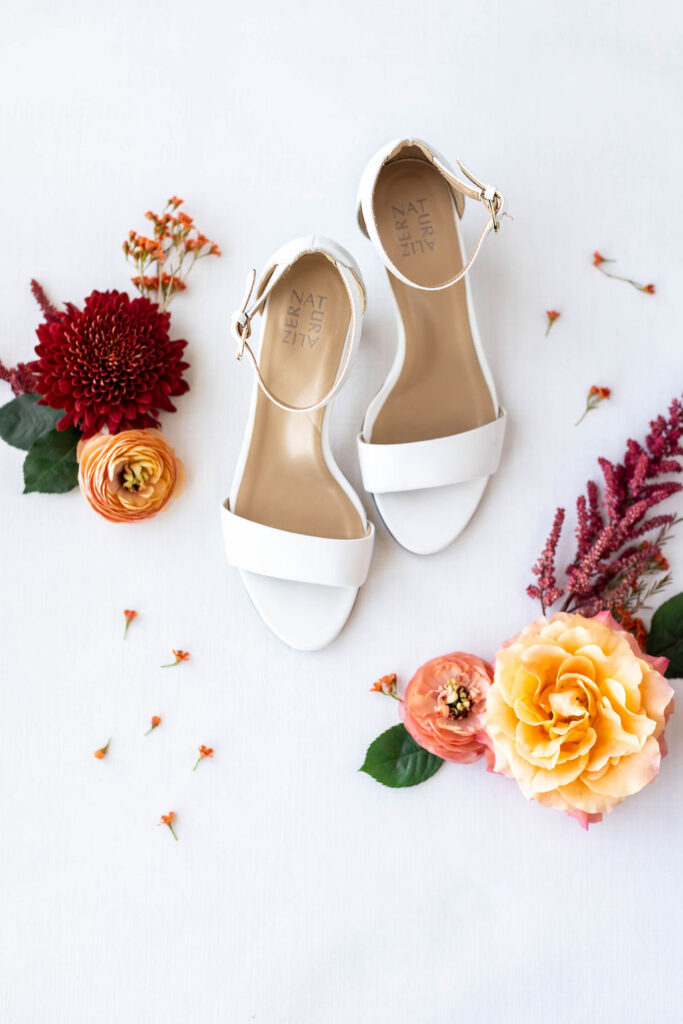 The wedding day flat lay consisting of the brides white shoes and flowers. | Photo by Texas Photographer Sarah Block Photography