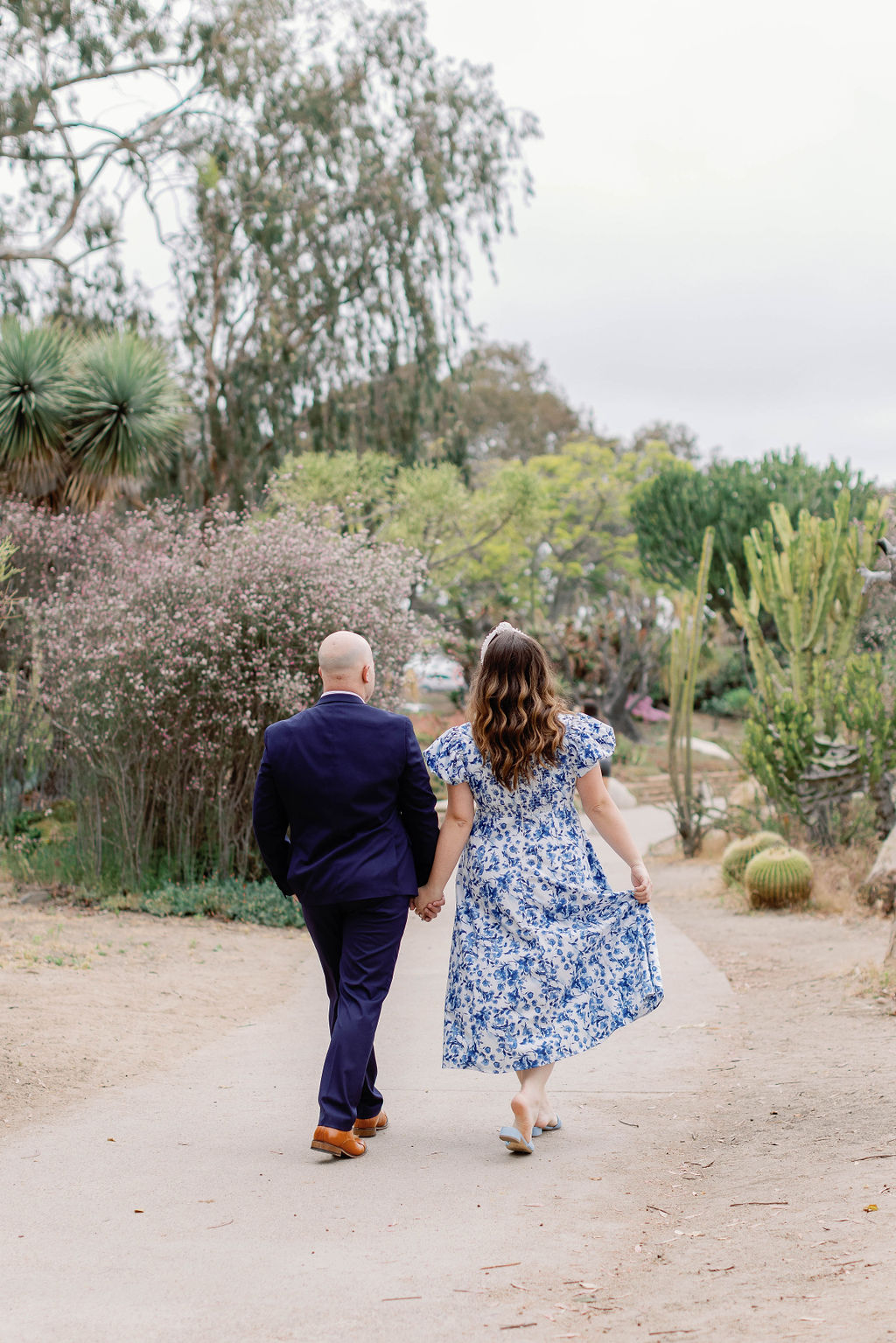 Engagement photo of Jimmy and Hannah  walking hand in hand with their backs to the camera through the gardens of Balboa Park. |Photo by California Photographer Sarah Block Photography