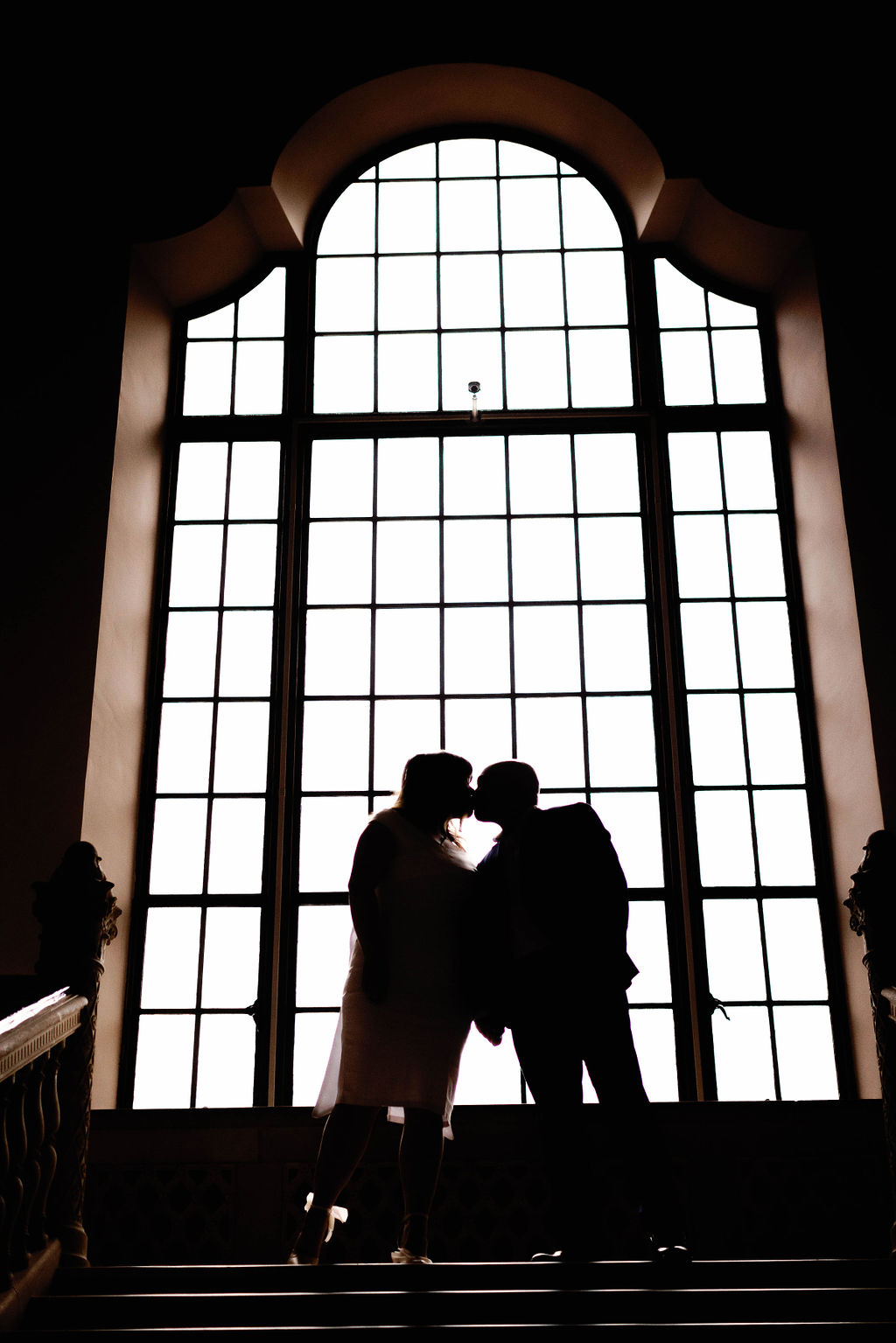 Hannah and Jimmy kissing in the window as they are silhouetted by the sunlight. |Photo by California Photographer Sarah Block Photography