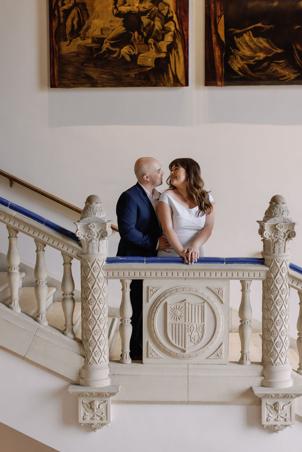 Engagement photo of Jimmy and Hannah overlooking the bannister of the stairs at San Diego Museum of art. |Photo by California Photographer Sarah Block Photography
