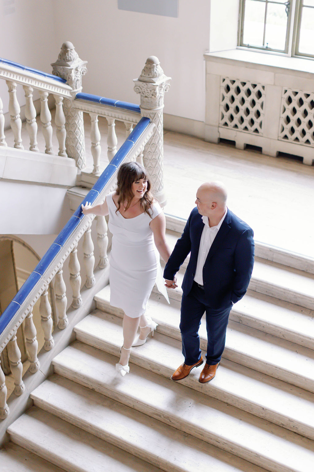 Lighter photo of Jimmy and Hannah walking down the stairs holding hands in the San Diego Museum of Art. |Photo by California Photographer Sarah Block Photography