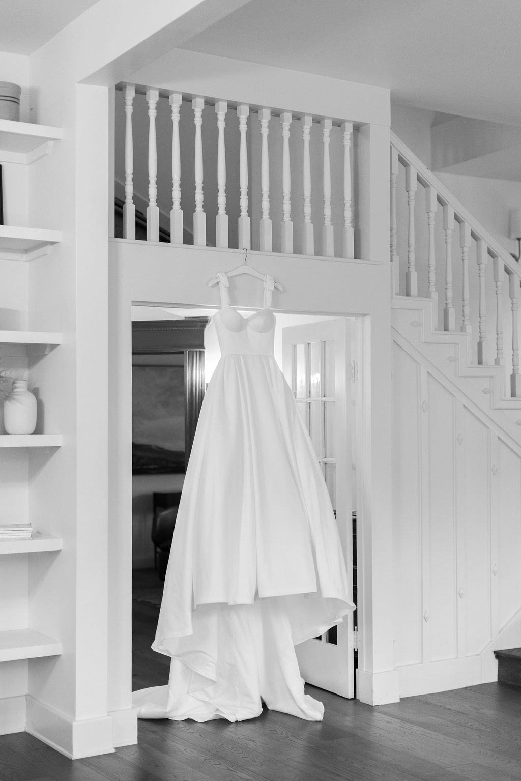 A black and white photo of the wedding gown hanging from the winding staircase in the Grand Lady wedding venue in Austin Texas | Photo by Sarah Block Photography