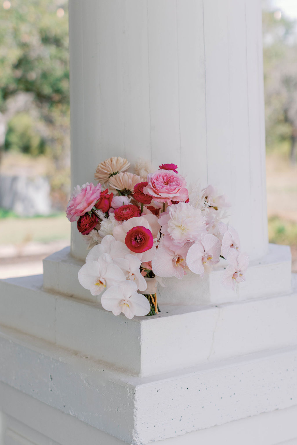 The wedding bouquet leans up against a pillar at The Grand Lady Wedding Venue in Austin Texas. It is made of hues of pink flowers. | Photo by Texas Wedding Photographer Sarah Block of Sarah Block Photography